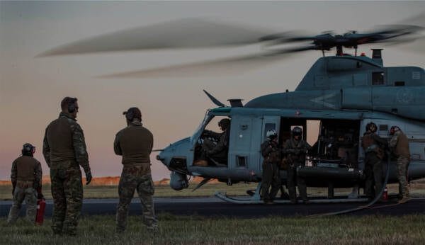 Soldiers prepare around a helicopter during refueling