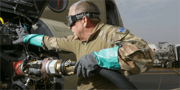 Technician connects a large fuel line to an aircraft intake port